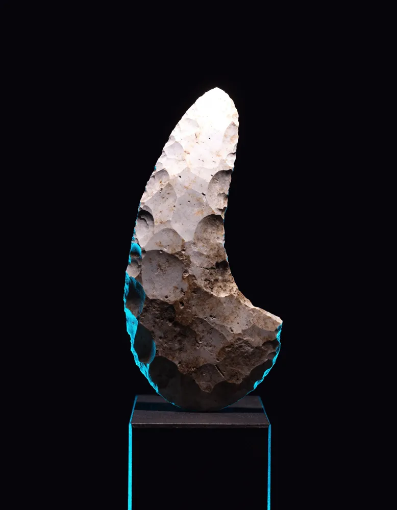 Ferramenta de pedra lascada iluminada num pedestal